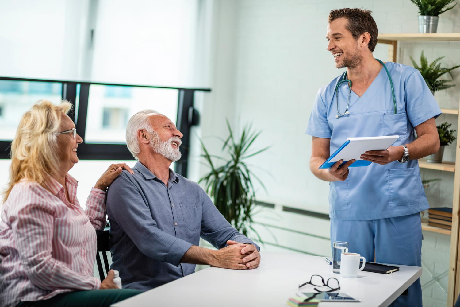 Seated man speaking with a person in blue scrubs in a clinical room